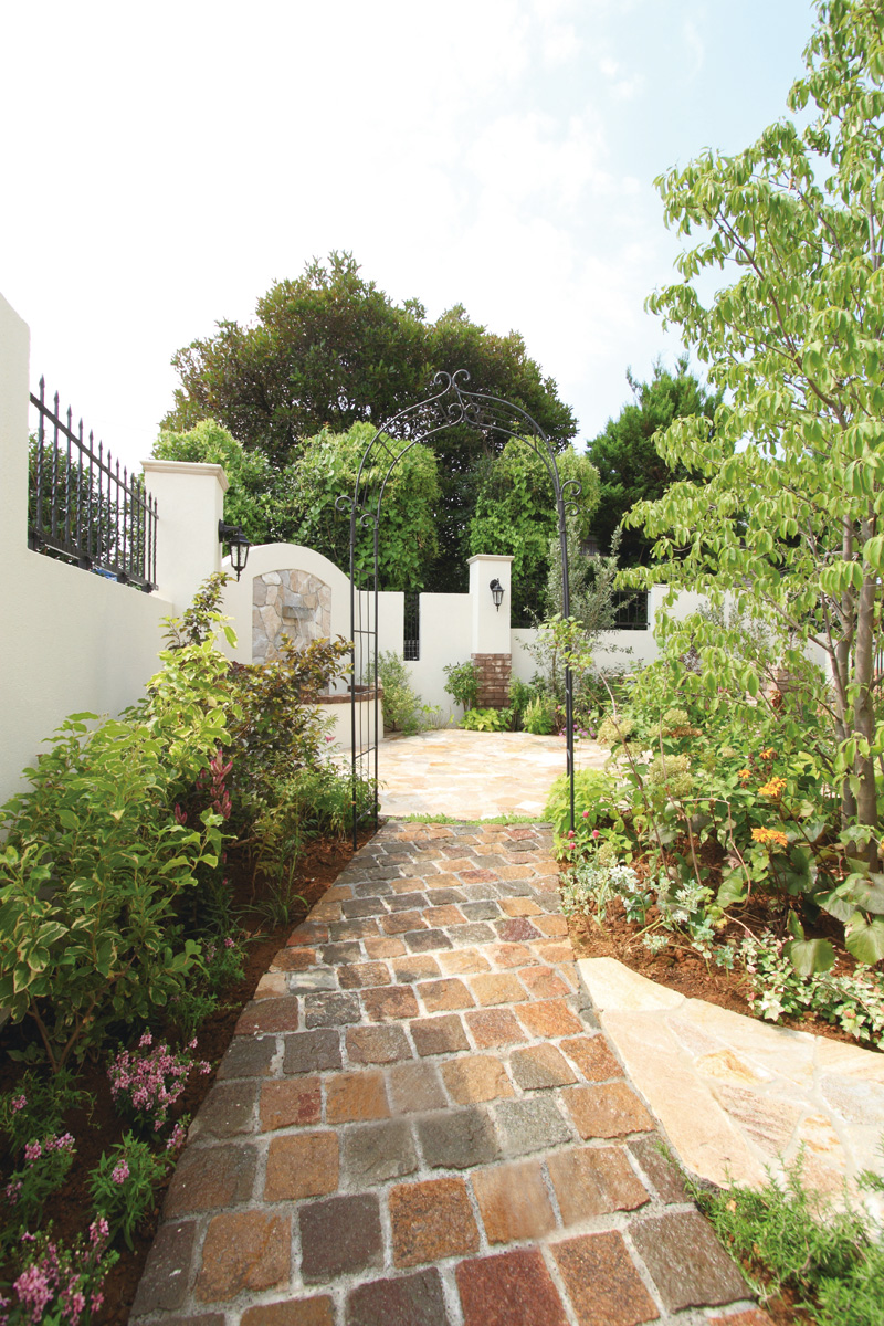 石畳の小道とアイアンのアーチがお庭へのアプローチを演出。