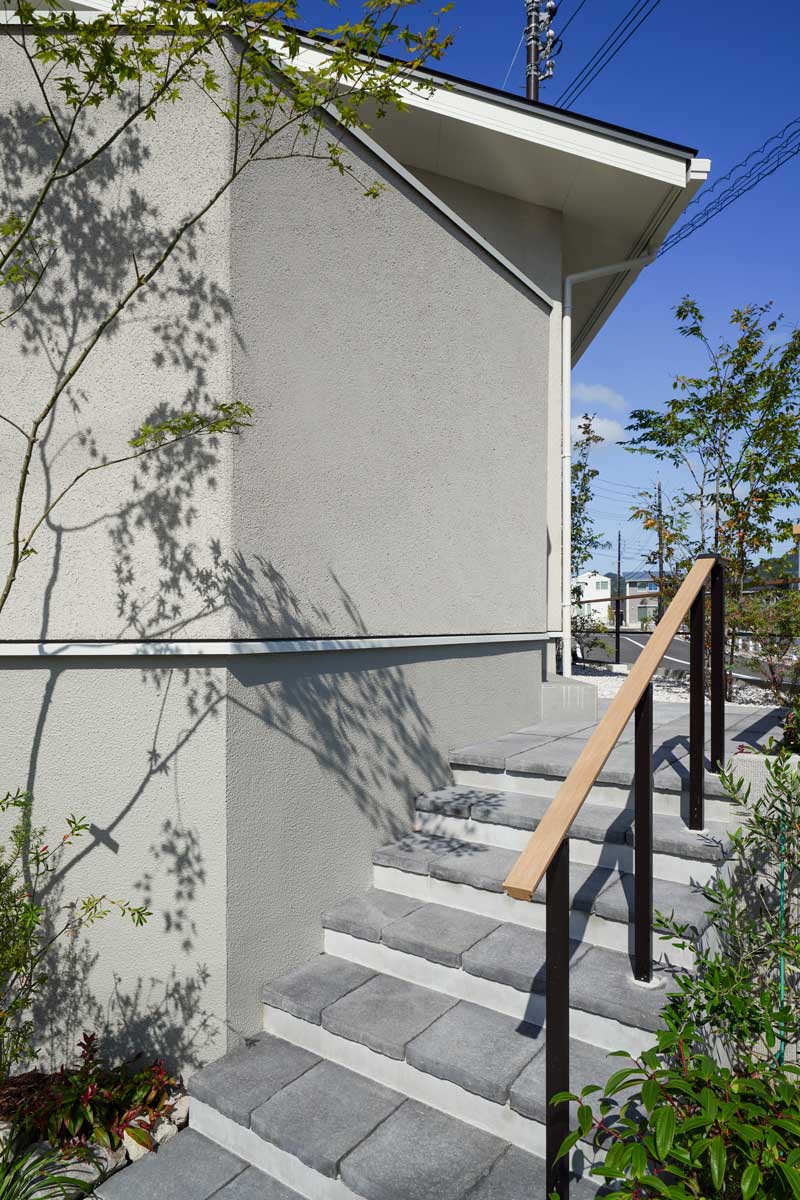 白い外壁と緑が織りなす、自然と調和した外構デザイン